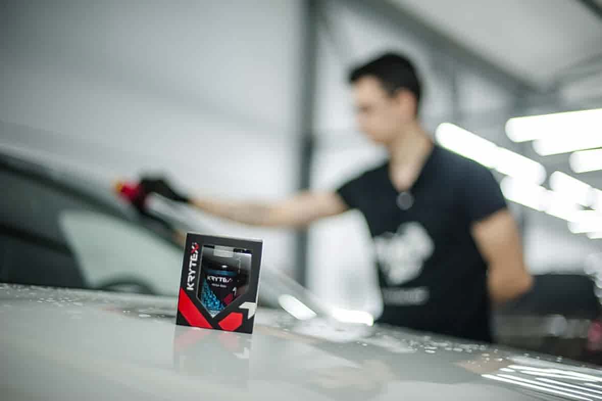 На фото упаковка с антидождем Krytex Mega Glass и мастер за работой
