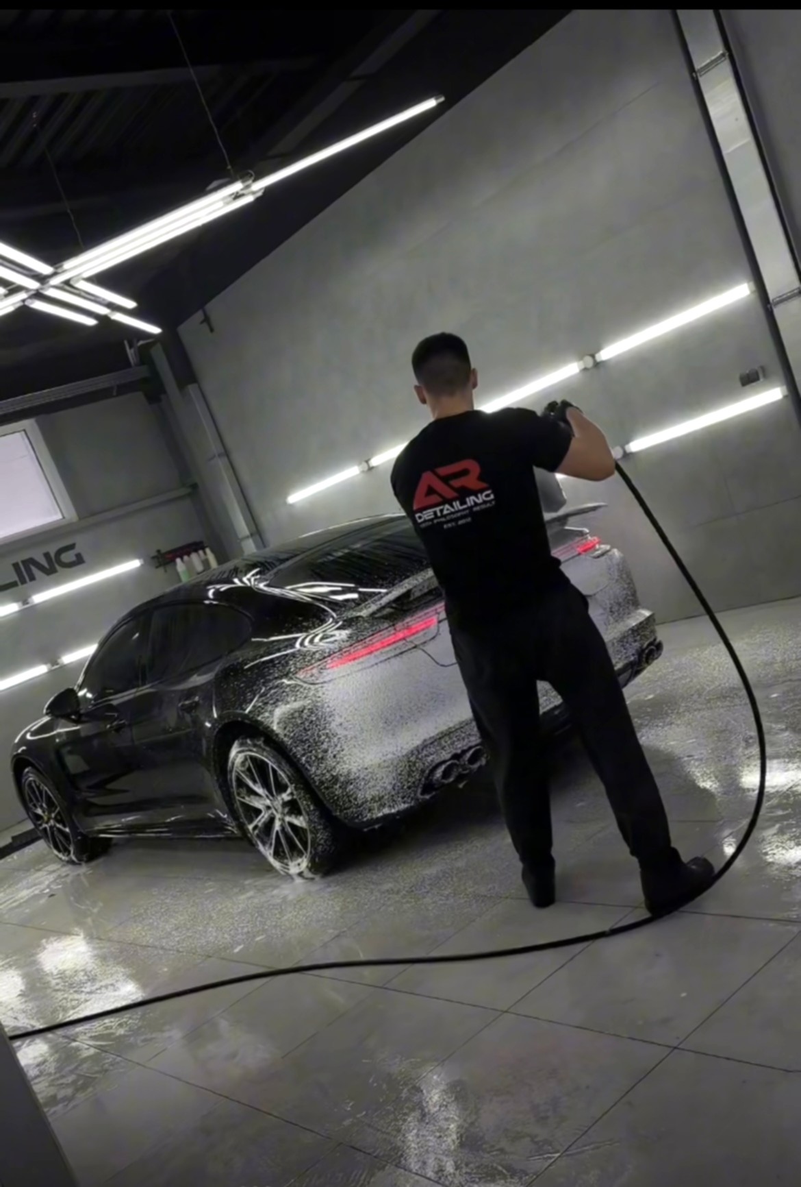 На фото технолог детейлинг-центра AR-Detailing кистью чистит эмблему на капоте автомобиля Porsche.